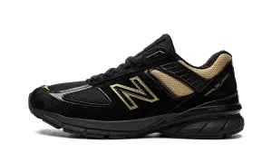 990v5 "Black / Gold" running in a snow - covered area shoes
